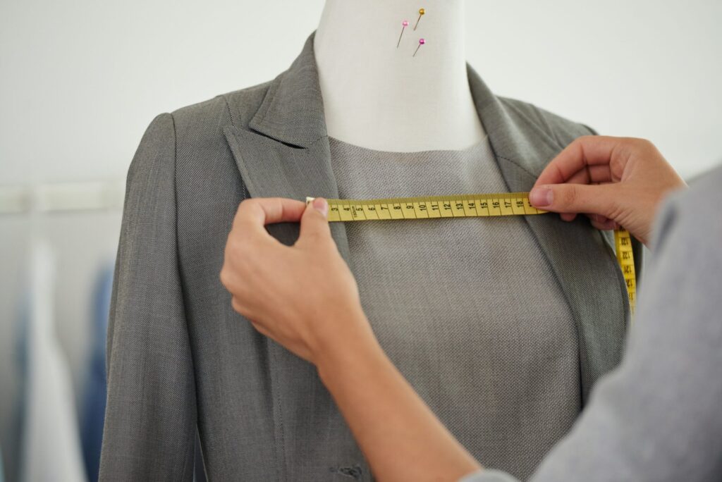 Manos de sastre midiendo traje femenino en maniquí